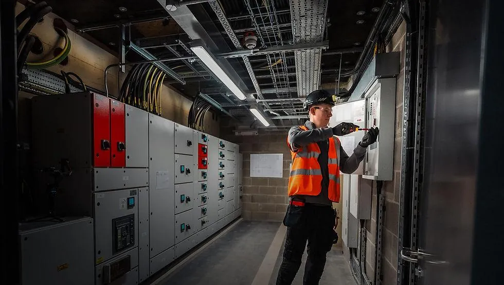 Electrician working on commercial electrical switchgear in a UK plant room